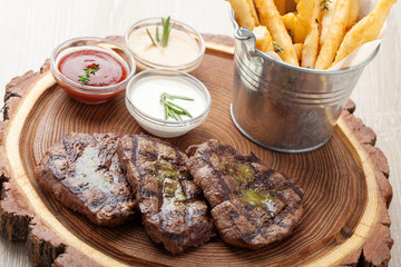 Portion of BBQ beef filet mignon with  sauces and fried potatoes