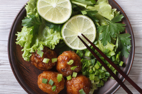Fish balls with salad and chopsticks close-up. top view