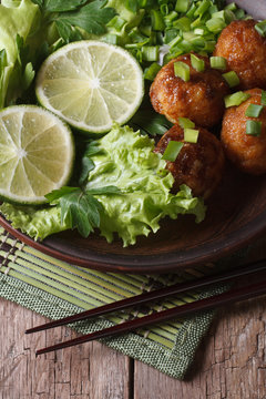 fish balls with lime and salad and chopsticks close-up. Vertical