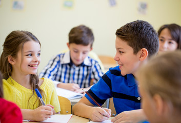 group of school kids writing test in classroom