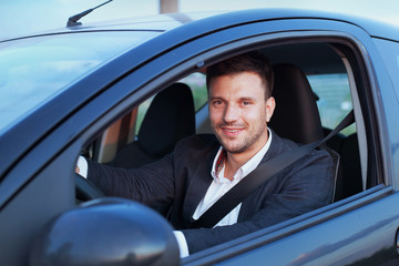 happy smiling driver in the car, portrait of young successful business man