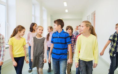 group of smiling school kids walking in corridor