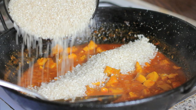 Making a traditional spanish paella. Adding rice.