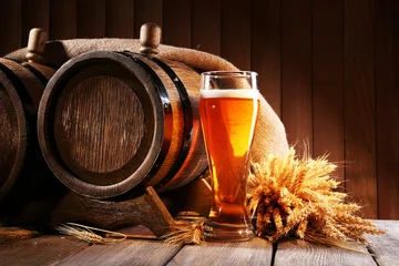 Poster Im Rahmen Beer barrel with beer glass on table on wooden background © Africa Studio