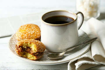Cup of coffee with tasty cookie on color wooden background