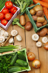 Different vegetables in boxes on wooden background top view