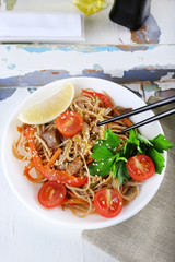 Chinese noodles with vegetables and roasted meat in bowl