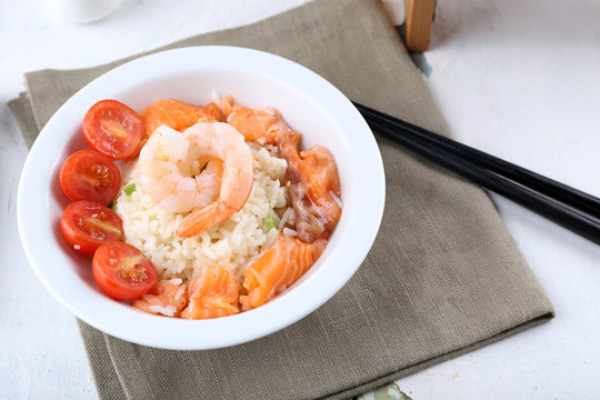 Boiled rice and shrimps, salmon and tomatoes in bowl,