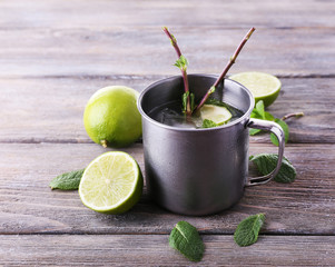 Lemonade in metal cup on wooden background