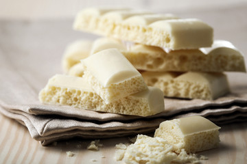 Tasty white porous chocolate on wooden table, close up