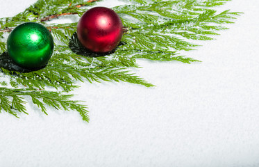 Two Christmas ornaments on cedar branch
