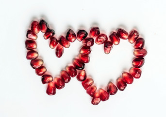 two hearts of pomegranate seeds isolated on white background