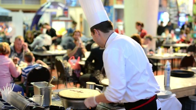chef prepares a pancake - restaurant with people in background