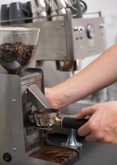 Barista with piston/portafilter grinding espresso beans.