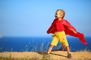 little boy dressed as superhero on the coast - 74064764