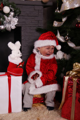 Fototapeta na wymiar crying baby Santa Claus by the fireplace