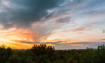 Summer sunset over the hills covered with forest