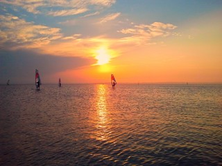 Fototapeta na wymiar Windsurfers in the sea with sun set