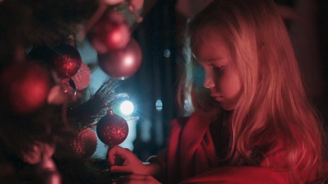 Beautiful little girl hangs on the Christmas tree Christmas