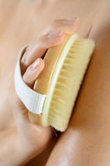 Frau massiert Arm mit Bürste