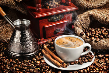 cup of coffee, grinder, turk and coffee beans on brown backgroun