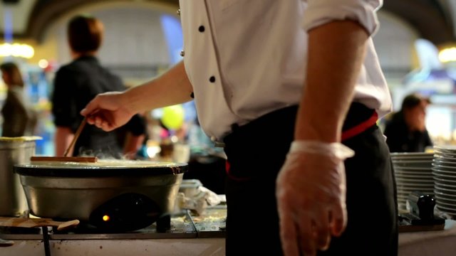chef prepares a pancake - people in background