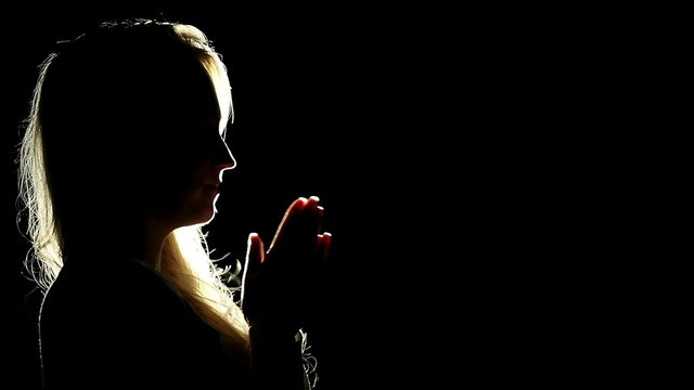 Silhouette of a woman who prays in the moonlight