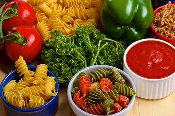 Variety of uncooked italian pasta with vegetables on wooden