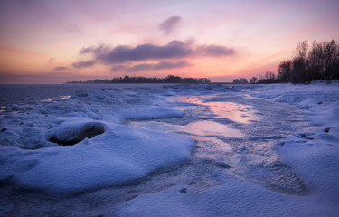 Winter landscape with frozen lake and sunset sky. Composition of