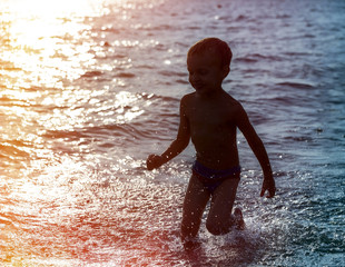 Silhouette of a boy running along the beach