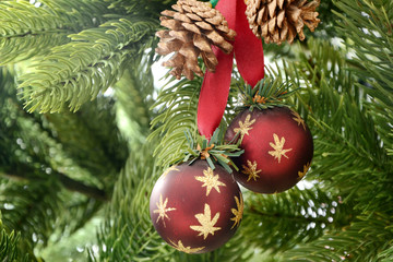 Dekorative rote Bälle mit goldene Stern und Zapfen auf grünem Weihnachtsbaum 