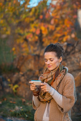 Happy young woman in autumn evening outdoors writing sms