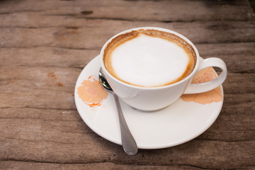 Cup of hot cappuccino coffee on wooden table.