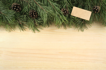 Christmas fir branches and wooden plate on a wooden background.