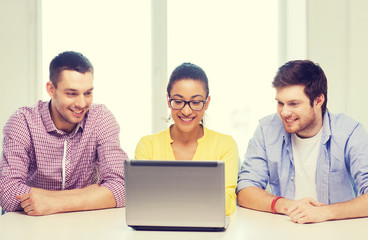 three smiling colleagues with laptop in office