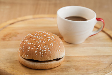 hamburgers and cup of black coffee on wooden board.