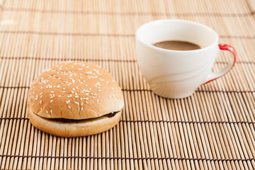 hamburgers and cup of black coffee on wooden board.
