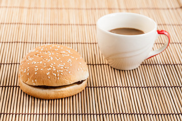 hamburgers and cup of black coffee on wooden board.