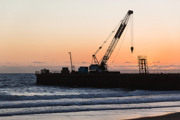 Obraz premium Beach Pier Crane Silhouetted Dawn