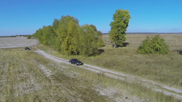 lonely car on  rural dirt road with shadow of drone. Aerial