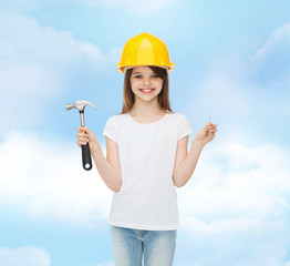 smiling little girl in hardhat with hammer