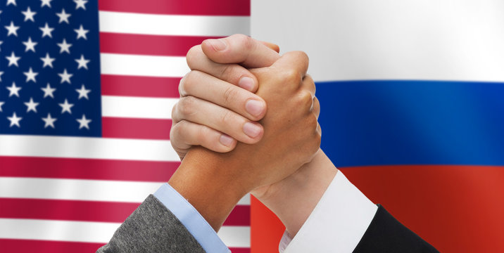 hands armwrestling over american and russian flags