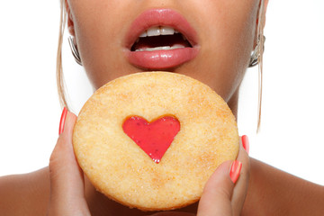 Heart-shaped cookie hold in front of female mouth
