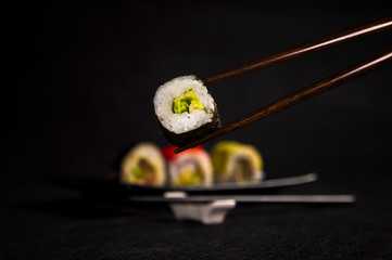Sushi on black background, japanese cuisine, chopsticks