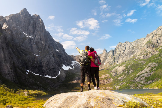 Young tourist couple standing  on stone near mountain lake