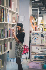 Beautiful young brunette posing in a bookstore