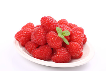 Ripe fresh raspberry with mint on plate over white