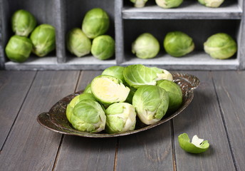 Fresh raw brussels sprouts in metal plate on  wooden background