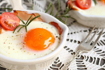Fried egg with bacon and tomato in ceramic pan