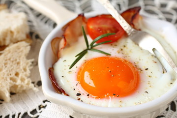 Fried egg with bacon, tomato, rosemary and sliced bread